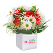 Overflowing with the cheerful hues of a Merton spring, this rounded bouquet bursts with coral, peach, and radiant red carnations, their frilled blooms cascading in a lush tumble from a gleaming white gift bag. Bright white daisies with green-yellow centers dance among the ruffled carnations, offering playful contrast and a sunny touch reminiscent of flower beds along Wimbledon Chase. Wisps of delicate baby's breath are laced between the blooms, adding a subtle, whisper-light texture that lifts the whole composition. On the left, small buds tinged in gentle violet peek through, suggesting the unfolding surprises of Merton's parks in early morning. Encasing the bouquet, gleaming, thick green leaves gently arch around the base, unifying the palette and promising lasting freshness. Presented in a sturdy, elegantly designed carrier bag, complete with soft ribbon handles, the arrangement feels perfect for gifting-a birthday surprise, a heartfelt thank you, or just a burst of joy to brighten a home from Morden to Colliers Wood. Every stem is placed with expertise and care, radiating love, vibrance, and the spirit of skilled local floristry in SW19.
