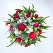 From a high, top-down view, this generous bouquet fills the frame against a spotless white background, its colours glowing as if freshly arranged on a Merton florist's workbench. At the centre, deep crimson red roses cluster together, some still tightly furled and others just beginning to open, their velvety petals layered like soft silk and suggesting quiet romance and enduring affection. Nestled between them are rich fuchsia and ruby-red carnations, their ruffled, full blooms adding a festive, almost playful texture that feels perfect for birthdays, anniversaries, or a spontaneous I'm thinking of you delivery across Merton. Bright white spray chrysanthemums and other daisy-like flowers punctuate the arrangement, their crisp petals radiating from golden centres to bring a sense of freshness and clarity, like clear morning light over Morden Hall Park. Threaded delicately through the composition, countless tiny gypsophila blossoms-airy clouds of baby's breath-soften every edge, creating a misty veil that makes the reds and greens appear even more vivid. Surrounding and supporting the blooms is a rich frame of foliage: broad, pointed dark green leaves, likely from lilies or alstroemeria stems, give structure and direction, guiding the eye in a gentle circular motion around the bouquet. Interspersed are rounded, silvery-green eucalyptus leaves that introduce a modern, slightly muted tone and suggest a cool, clean fragrance, reminiscent of a walk along the leafy streets near Wimbledon Chase. The overall composition is full and rounded, carefully balanced yet wonderfully abundant, like a generous armful of garden favourites freshly gathered for same-day delivery. This is a bouquet that visually speaks of joy, recovery, and heartfelt celebration-suited to sending love, thanks, or get-well wishes to someone special in and around Merton.