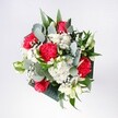 A hand-tied bouquet of red roses, deep red carnations, soft white daisies, and airy gypsophila rests against a neutral background, glowing as if caught in gentle morning light over Merton. The velvety roses form the confident heart of the arrangement, their petals rich and layered, while the carnations curl around them in ruffled folds, adding a feathery texture that feels both passionate and inviting. Small, snow-white daisy chrysanthemums cluster between the red blooms, their bright yellow hearts lending an innocent, cheerful sparkle, like the first brightness over Wimbledon Common. Wisps of baby's breath weave delicately throughout, tiny white stars that soften every edge and create a sense of movement and celebration, as if the bouquet is mid-laughter. Eucalyptus stems and broad tropical greens frame the flowers, their cool blue-green tones and sculpted leaves bringing a modern, stylish balance that keeps the design from feeling too formal. The structure is full yet breathable, each flower given space to be seen, echoing the careful hands of a local Merton florist who understands when to let nature lead. You can almost sense the gentle, fresh fragrance-herbal eucalyptus mingling with classic rose and the faint sweetness of daisies. The bouquet feels perfect for marking joyful milestones: a promotion in one of the offices near Morden, a welcome-home surprise after a commute through Colliers Wood, or a simple thinking of you left on a kitchen table. It is a composition that radiates optimism and quiet excitement, like the beginning of a special day, captured in petals and leaves.